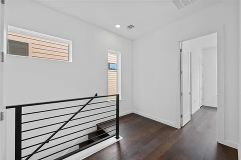 a view of a hallway with wooden floor and stairs