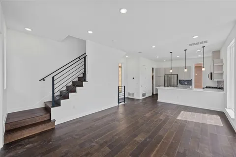 a view of an empty room with wooden floor and stairs