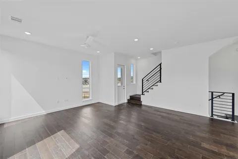 a view of an empty room with wooden floor and cabinets