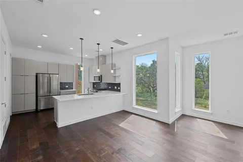 a large white kitchen with stainless steel appliances granite countertop a refrigerator oven a sink and a large window