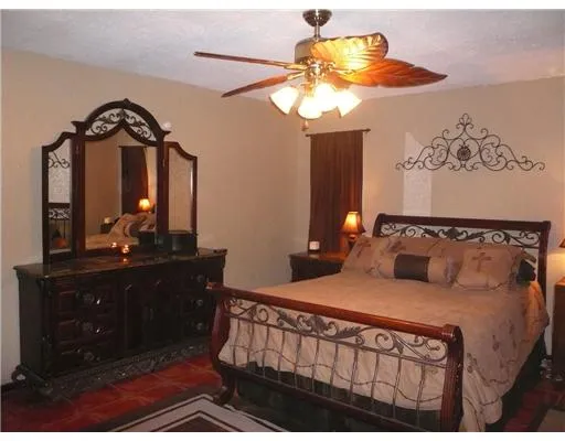 a bedroom with a bed mirror on dresser and a chandelier
