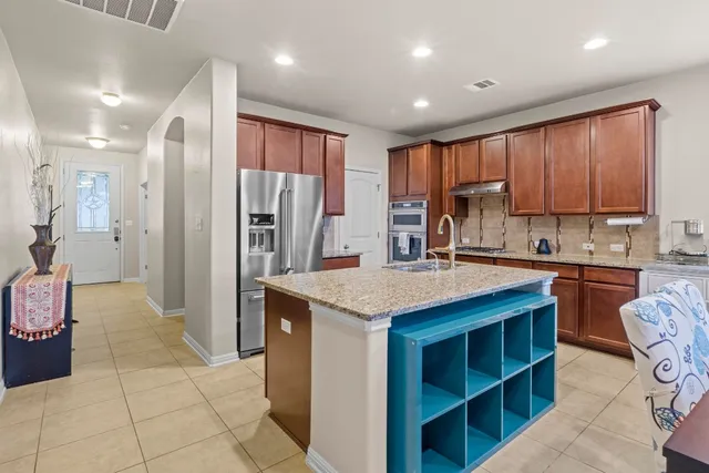 a kitchen with stainless steel appliances granite countertop a refrigerator a stove and a sink with wooden cabinets
