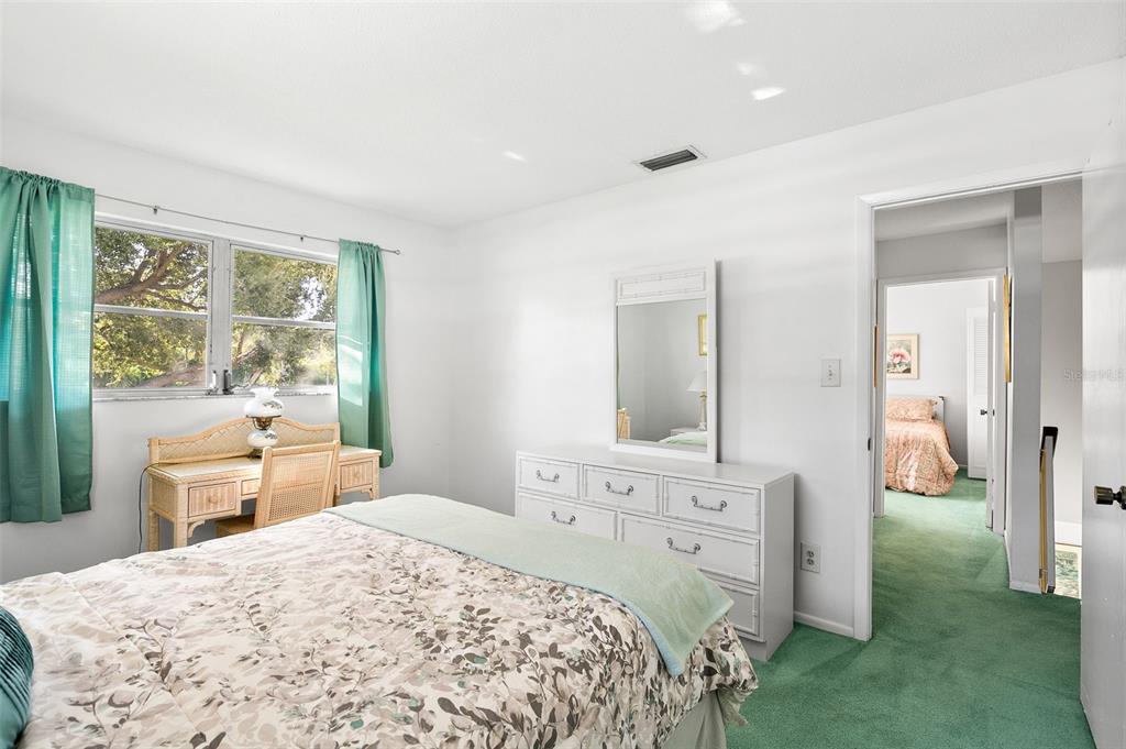 597 Sutton Place Longboat Key, FL 34228 - Photo 19 of 49 a spacious bedroom with a bed and a dresser with mirror