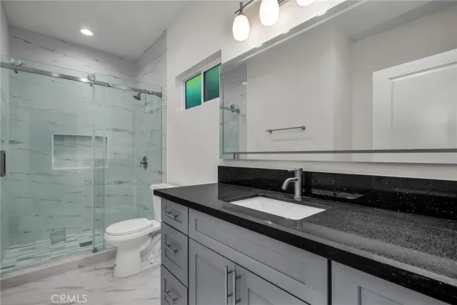 a bathroom with a sink a toilet a mirror and shower