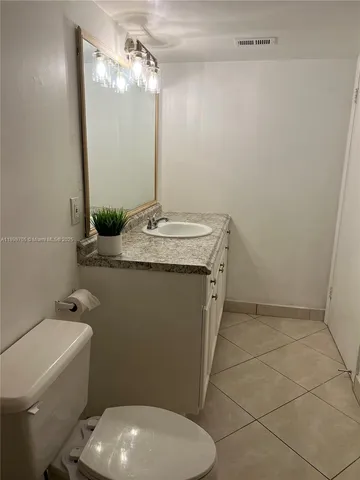 a bathroom with a granite countertop toilet and a sink