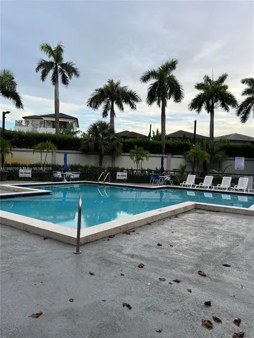 a view of swimming pool with a yard and palm trees