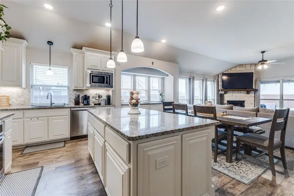 a kitchen with stainless steel appliances granite countertop a sink a stove and a wooden floors