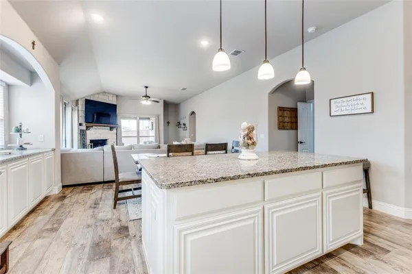 a large kitchen with kitchen island a stove a sink a center island and wooden floor