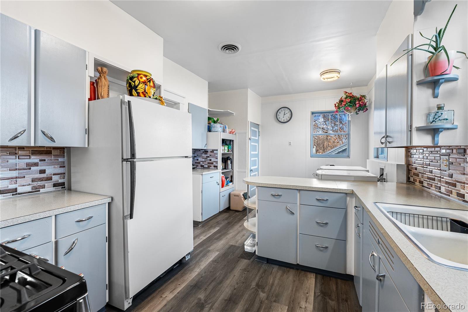 6145 West 38th Avenue Wheat Ridge, CO 80033 - Photo 11 of 39 a kitchen with a refrigerator a sink and wooden floor