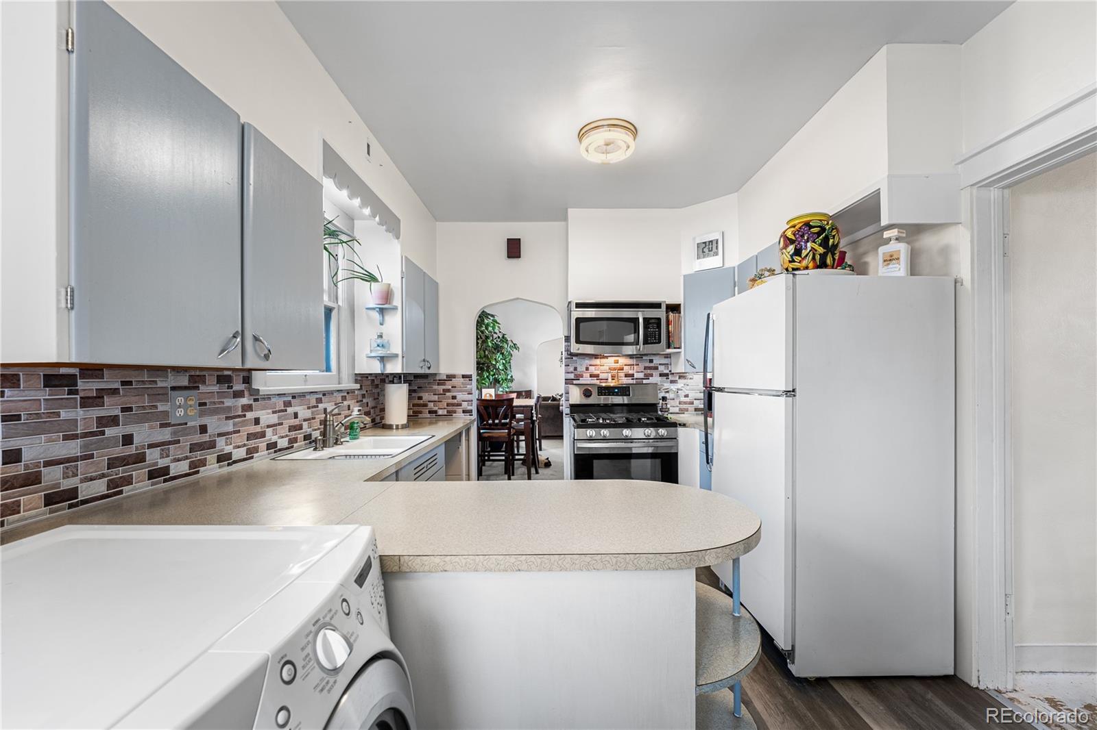 6145 West 38th Avenue Wheat Ridge, CO 80033 - Photo 13 of 39 a kitchen with refrigerator and white cabinets