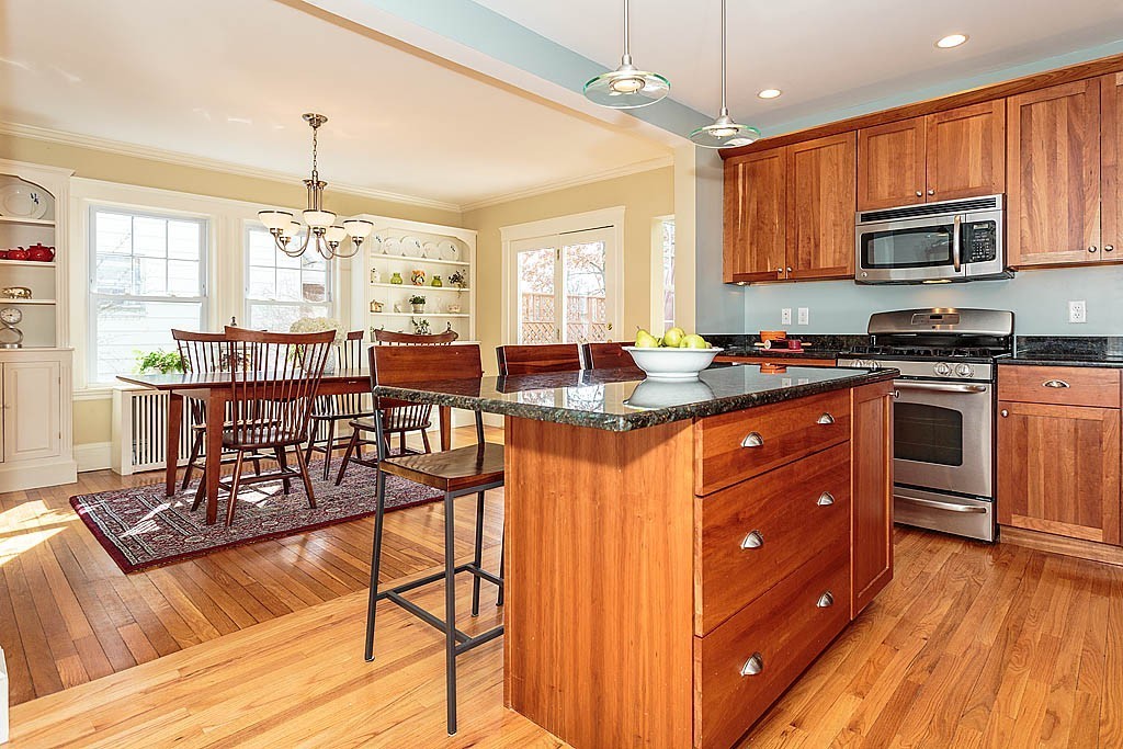 40 Kilsythe Road Arlington, MA 02476 - Photo 3 of 16 a kitchen with granite countertop a stove a sink dishwasher a dining table and chairs with wooden floor