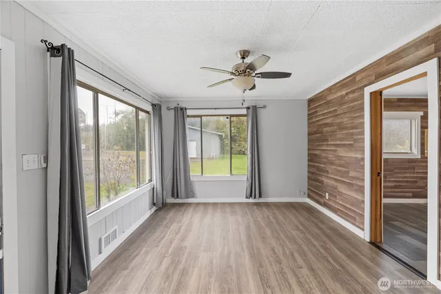a view of empty room with wooden floor and fan