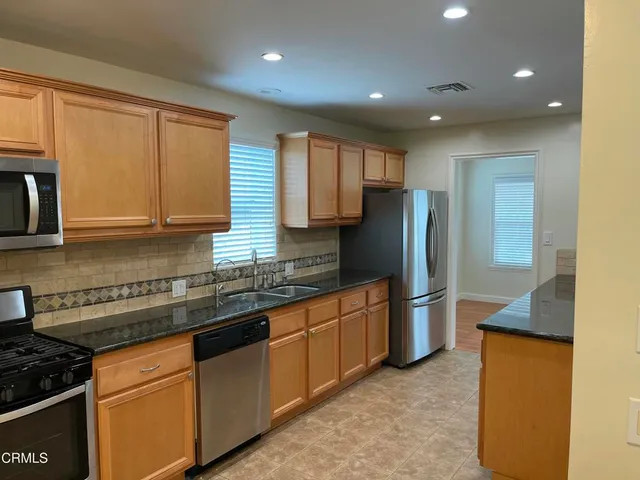 a kitchen with stainless steel appliances granite countertop a refrigerator sink and stove