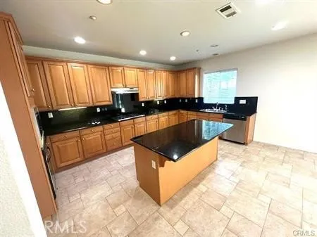 a kitchen with kitchen island granite countertop a sink a counter top space and cabinets