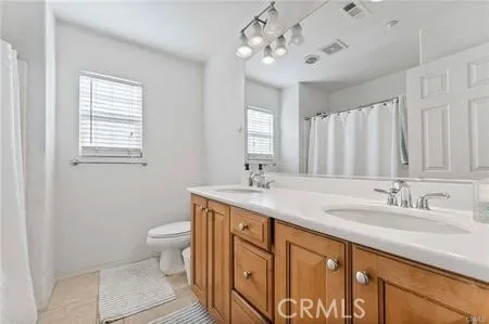 a bathroom with a double vanity sink a toilet and a mirror