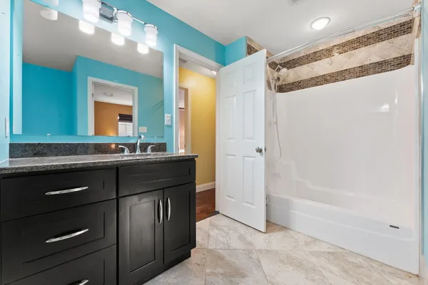 a bathroom with a granite countertop sink a mirror and a bathtub