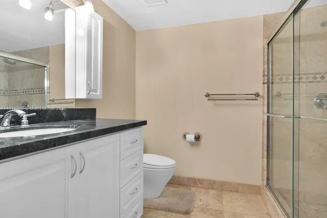 a bathroom with a granite countertop sink a toilet and a mirror