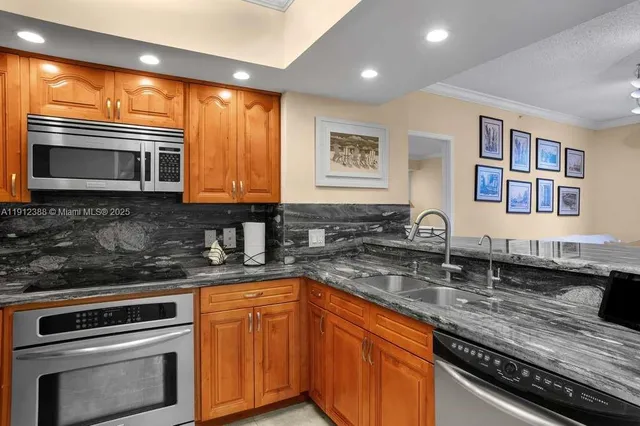 a kitchen with stainless steel appliances granite countertop a stove a sink and a microwave
