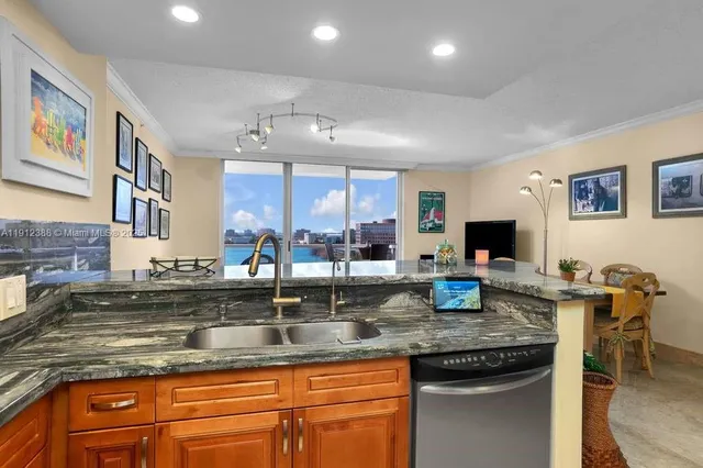 a kitchen with granite countertop kitchen island stainless steel appliances a sink stove and cabinets
