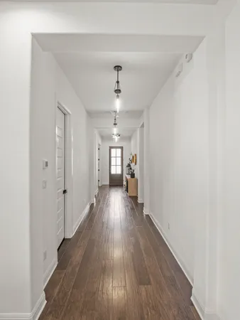 a view of a hallway with wooden floor and a ceiling fan