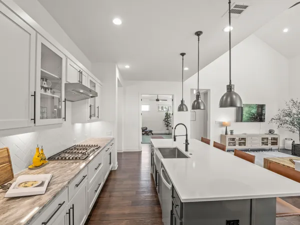 a kitchen with stainless steel appliances kitchen island granite countertop a sink a stove and a wooden floors