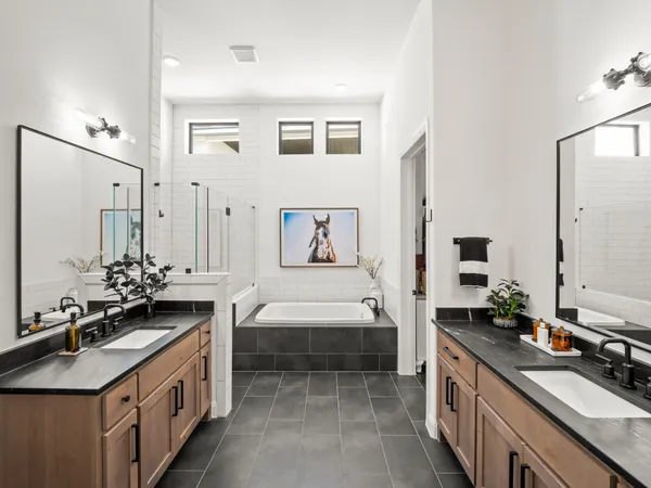 a spacious bathroom with a double vanity sink a mirror a bathtub and a shower