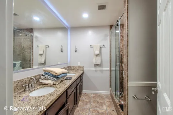 a bathroom with a granite countertop sink a mirror and a shower