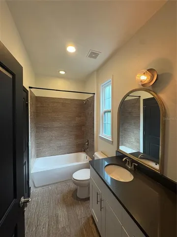 a bathroom with a granite countertop toilet a sink and a window
