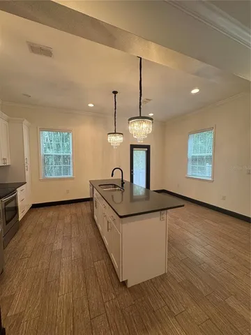 a kitchen with stainless steel appliances granite countertop a sink a stove a dining table and chairs with wooden floor