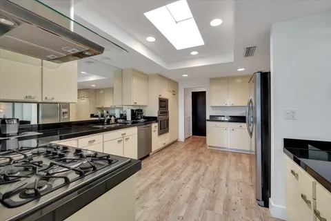 a large kitchen with stainless steel appliances kitchen island granite countertop a stove and a refrigerator