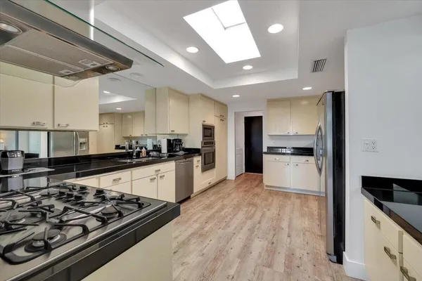 a large kitchen with stainless steel appliances kitchen island granite countertop a stove and a refrigerator