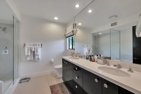 a bathroom with a double vanity sink a toilet and shower