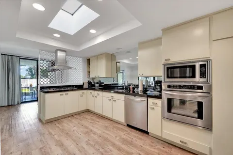 a kitchen with stainless steel appliances granite countertop a stove top oven a sink and a microwave