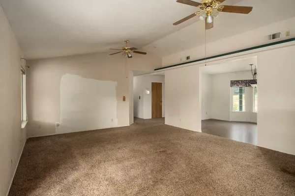 a view of a big room with a chandelier fan and windows