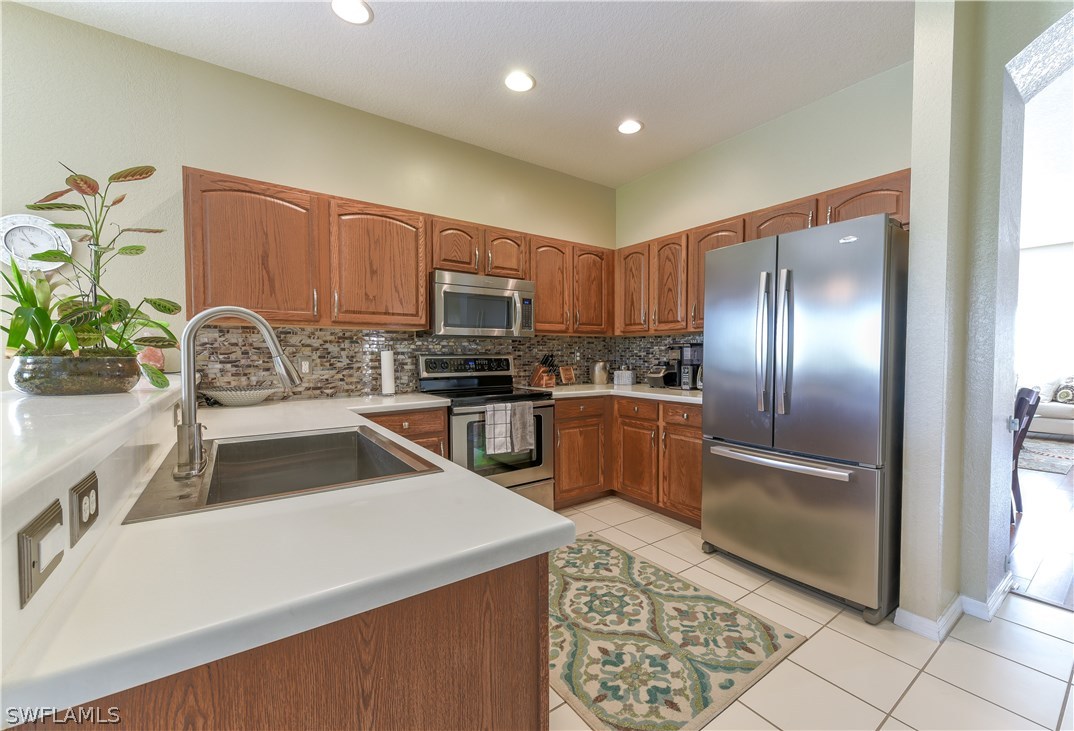 8249 Silver Birch Way Lehigh Acres, FL 33971 - Photo 3 of 19 a kitchen with granite countertop a refrigerator and a sink