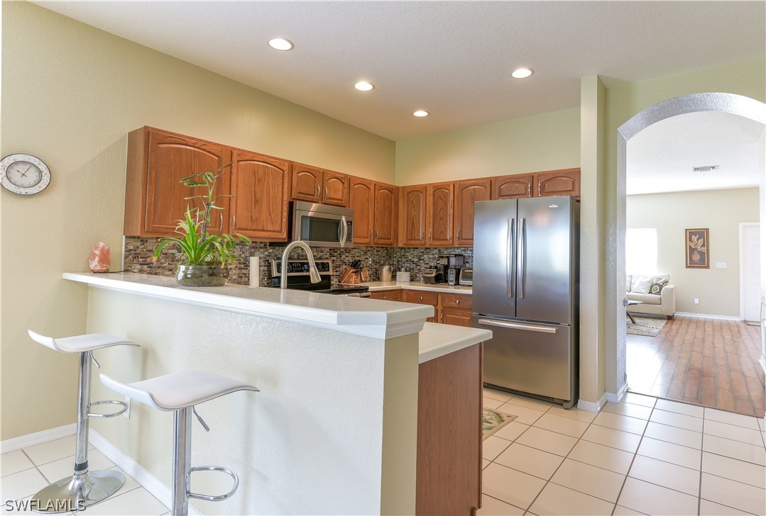 8249 Silver Birch Way Lehigh Acres, FL 33971 - Photo 4 of 19 a kitchen with stainless steel appliances granite countertop a refrigerator and a stove top oven