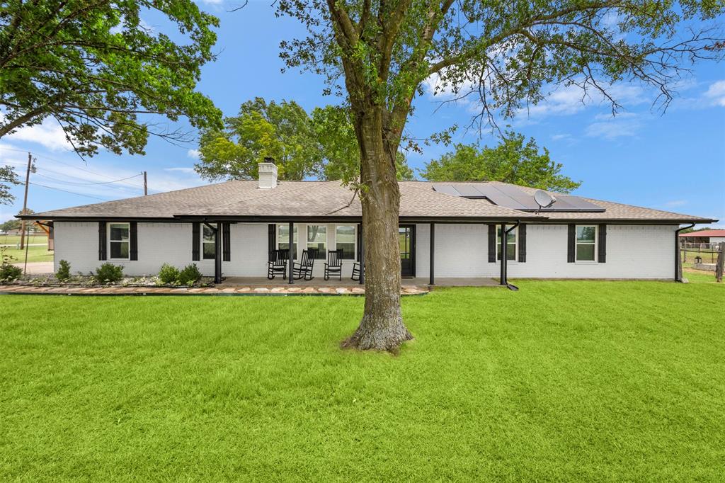 6754 Raymond Road Kaufman, TX 75142 - Photo 35 of 38 Expansive green lawn surrounds a white-painted brick exterior with black shutters and a covered patio
