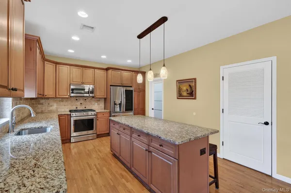 a kitchen with stainless steel appliances granite countertop a kitchen island hardwood floor sink and stove