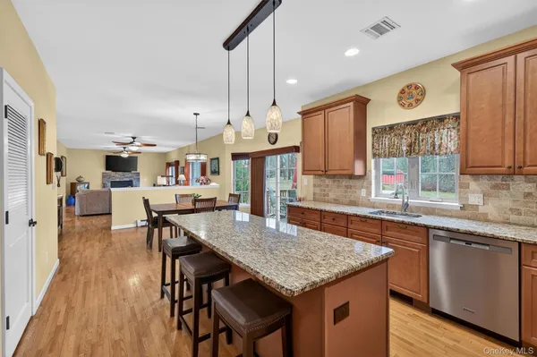a living room with stainless steel appliances granite countertop furniture wooden floor and a window