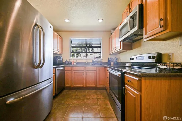 a kitchen with stainless steel appliances granite countertop a refrigerator and a sink