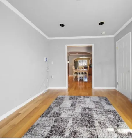 a view of a hallway view with wooden floor and a flat screen tv