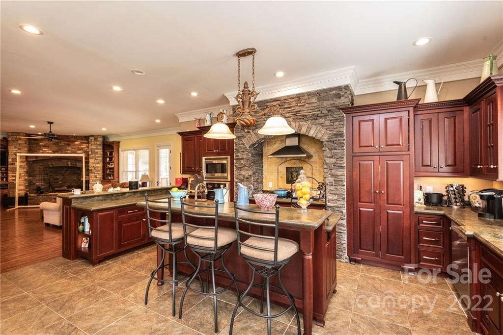 4597 Hickory Nut Ridge Road Granite Falls, NC 28630 - Photo 20 of 48 a kitchen with stainless steel appliances kitchen island granite countertop a refrigerator a stove a sink a dining table and chairs with wooden floor