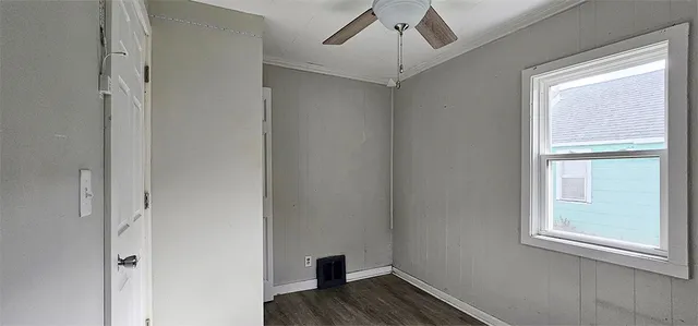 a view of empty room with wooden floor and fan