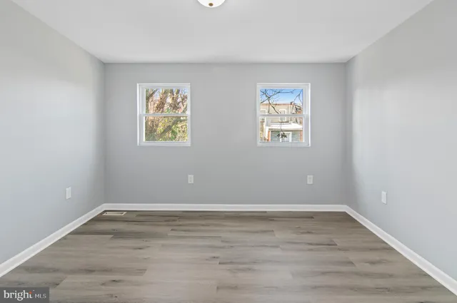 an empty room with wooden floor and window
