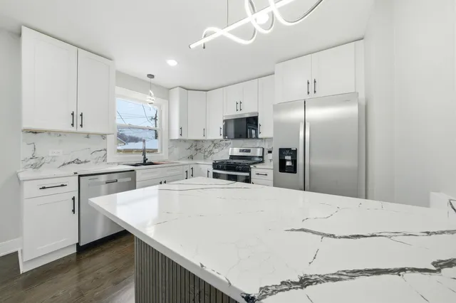 a kitchen with granite countertop a sink stainless steel appliances and white cabinets