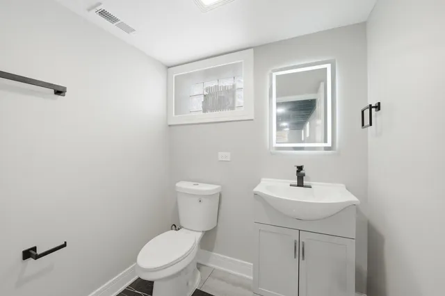 a bathroom with a toilet a sink and mirror