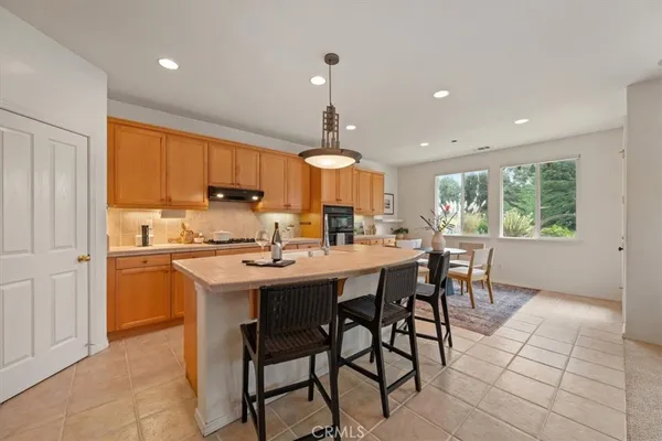 a kitchen with stainless steel appliances a dining table chairs stove and cabinets