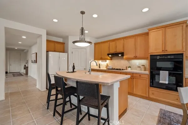 a kitchen with stainless steel appliances granite countertop a stove top oven a sink dishwasher and a refrigerator with wooden cabinets