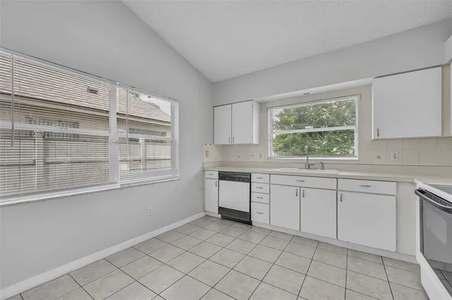 a kitchen with white cabinets and a window