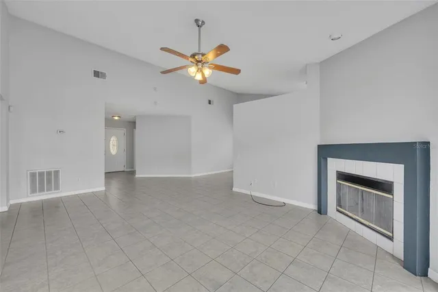 a view of an empty room and chandelier fan